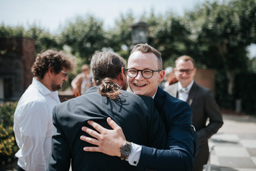 Junger Mann mit Brille umarmt den Bräutigam