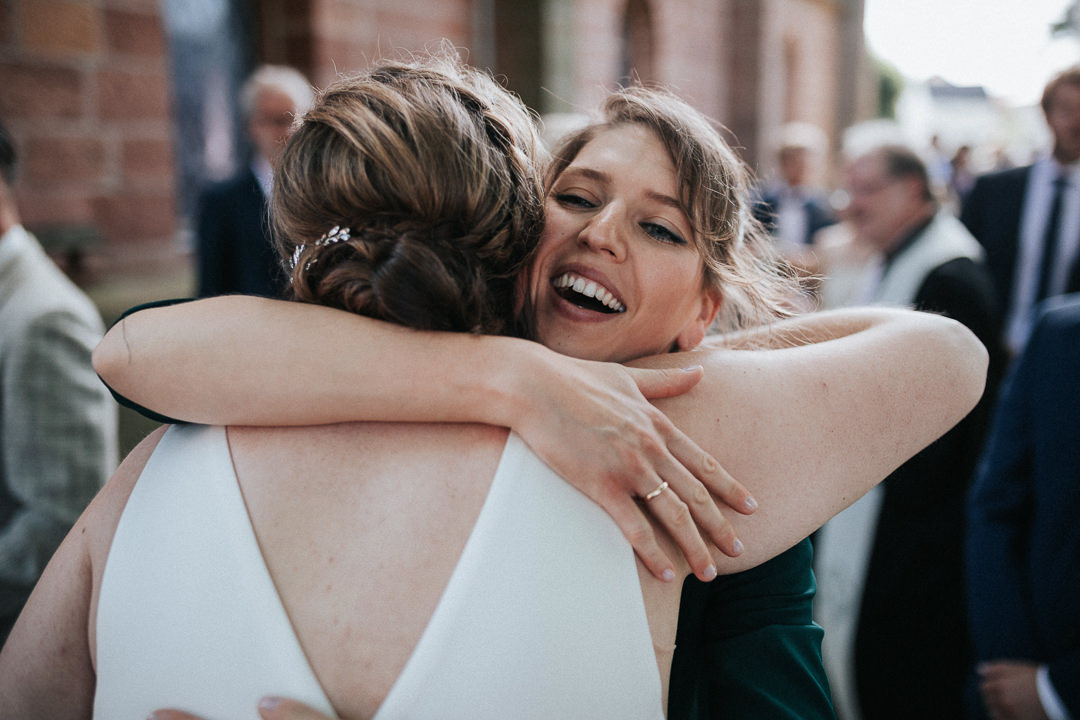 Frau umarmt die Braut und lacht