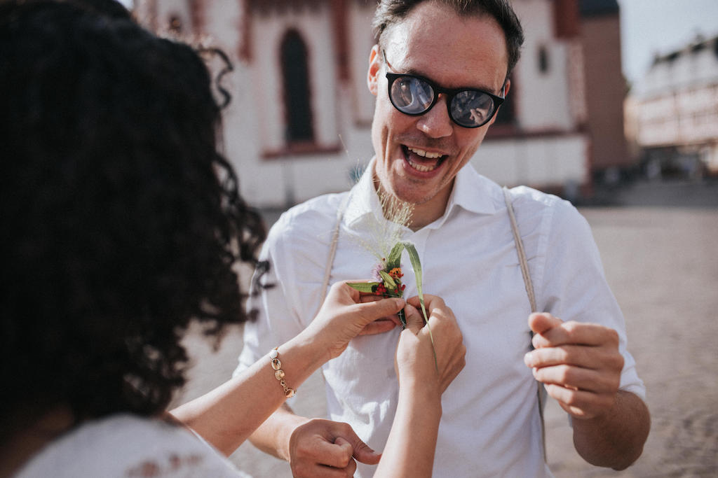 Hochzeit-auf-der-Backschaft-in-Frankfurt-Personen Braut bringt Gast eine Ansteckblume an