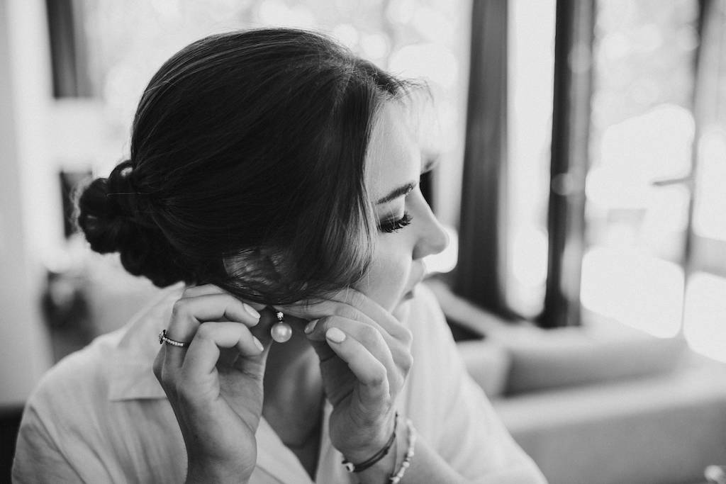 Hochzeit-Burg-Schwarzenstein-Getting-Ready.jpg Braut steckt sich einen Ohrring an.