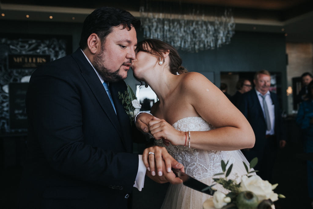 Hochzeit-auf-Burg-Schwarzenstein-Empfang-Muellers.jpg Braut gibt dem Bräutigam einen Kuss beim Tortenanschnitt.