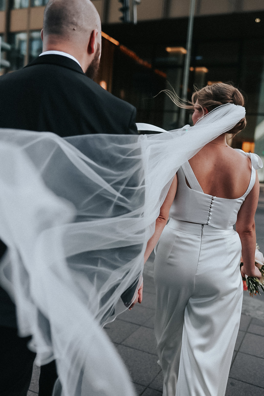 braut von hinten läuft und ihr schleier weht im wind.
